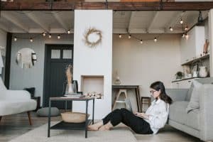 Woman sitting on the floor with a laptop in a cozy living room, showcasing a modern home environment ideal for home buying insights.